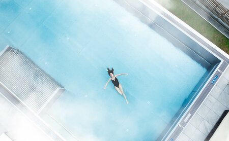 Frau schwimmt im Infinity Pool