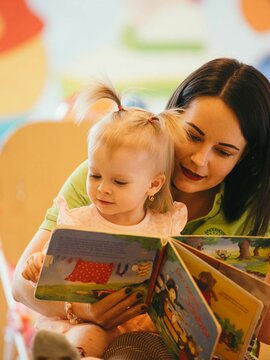 Betreuerin mit Baby beim Buchlesen
