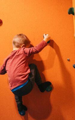 Junge auf der Kletterwand im Familienspielraum