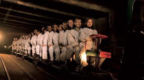 Touristen sitzen auf dem Zug in die Stollen des Salzbergwerks Hallein
