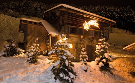 Weihnachtliche Stimmung am Abend draußen im Schnee mit Hütte